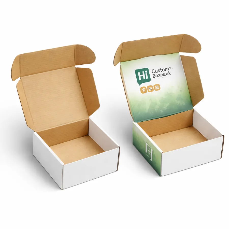Two open cardboard mailing boxes- one plain white and one with a green branded lid- class=